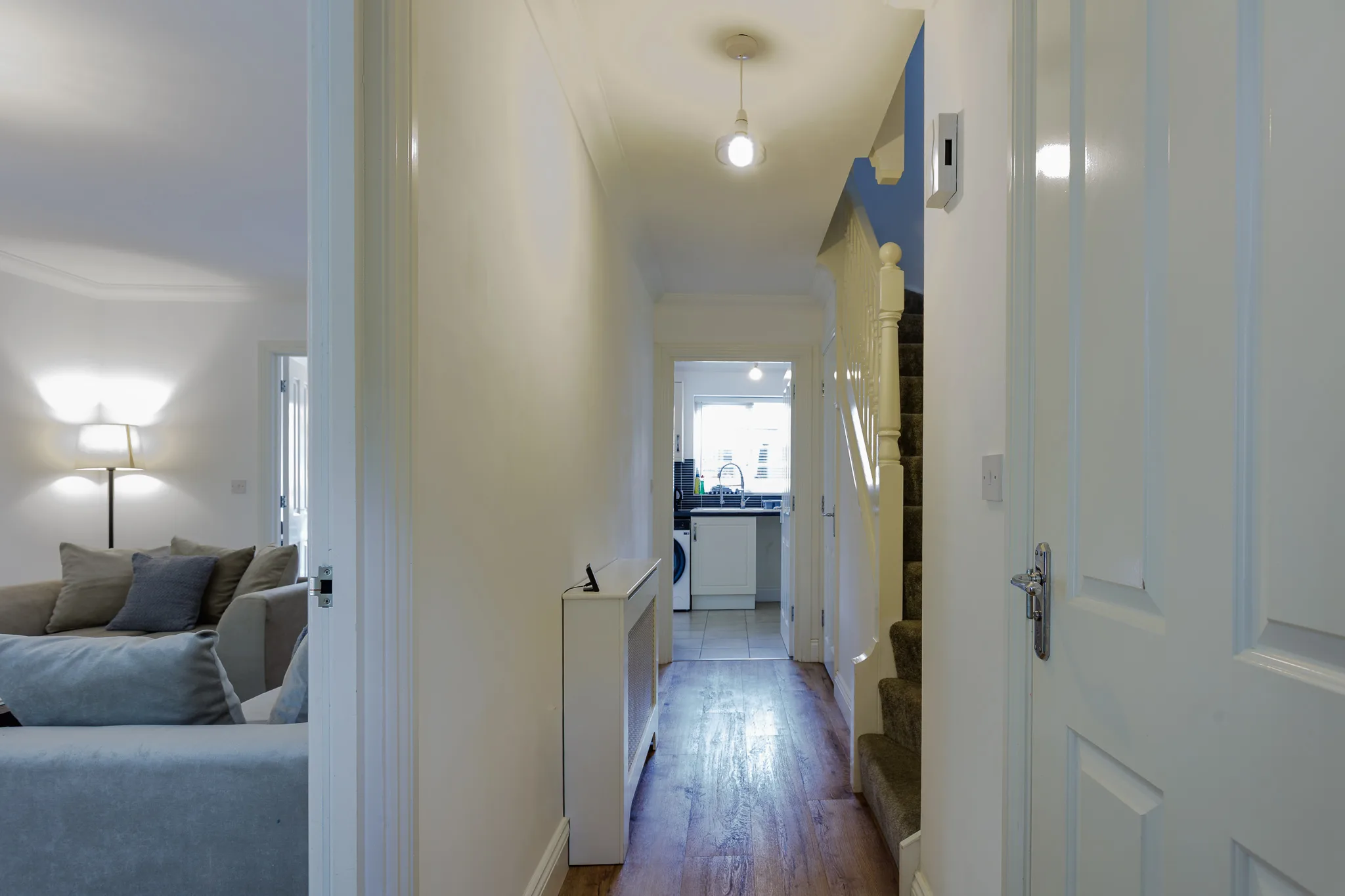 Modern hallway with cream walls, dark wood flooring, pendant light