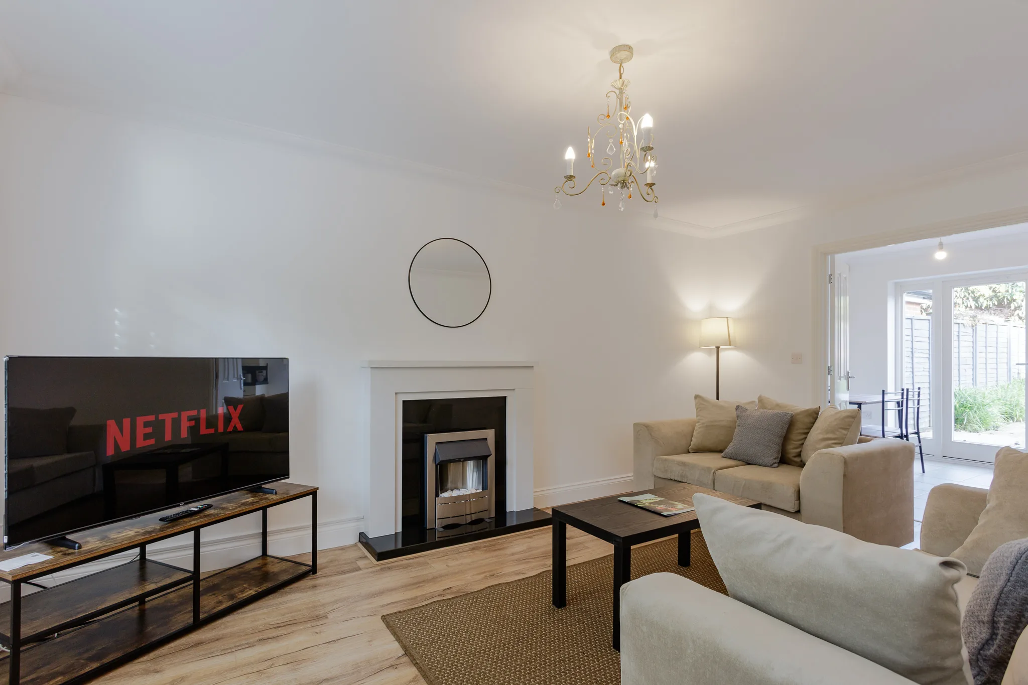 Modern living room with fireplace, TV, and elegant chandelier