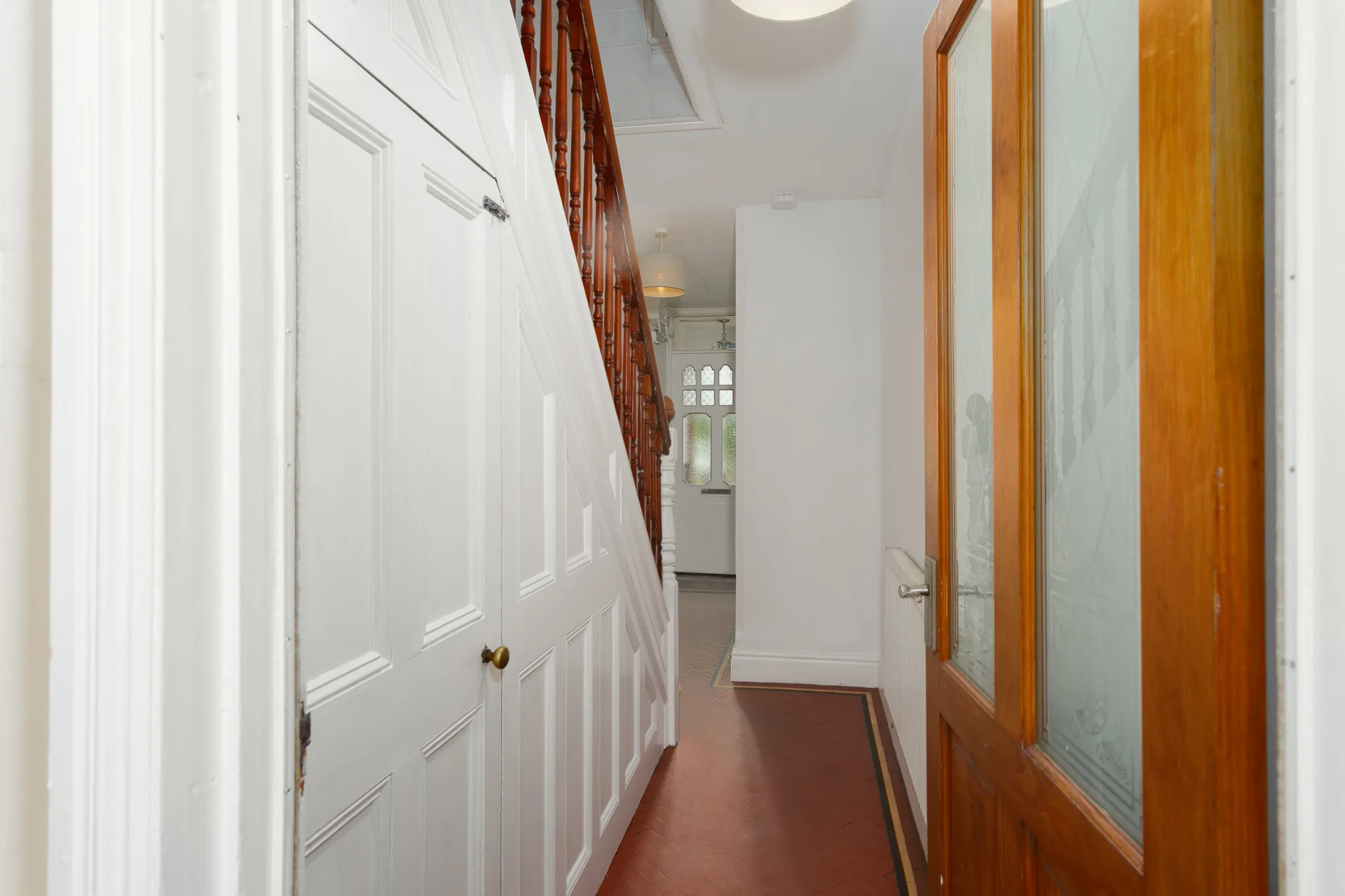Bright hallway with white doors and wooden staircase