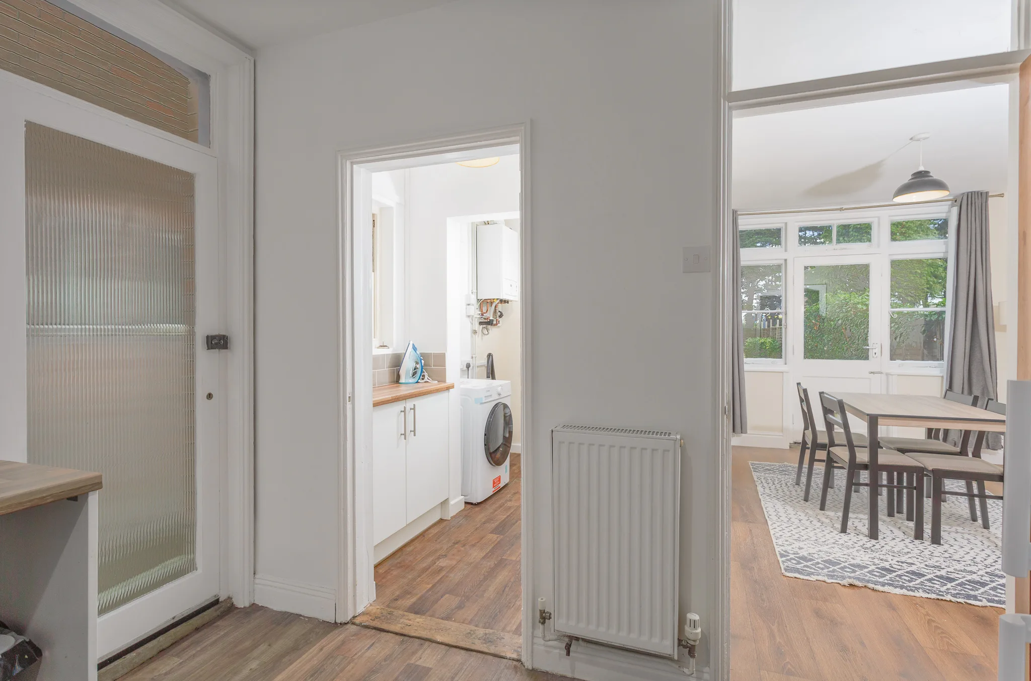 Hallway, utility and dining room of a Suffolk holiday let shown in one frame with the garden beyond