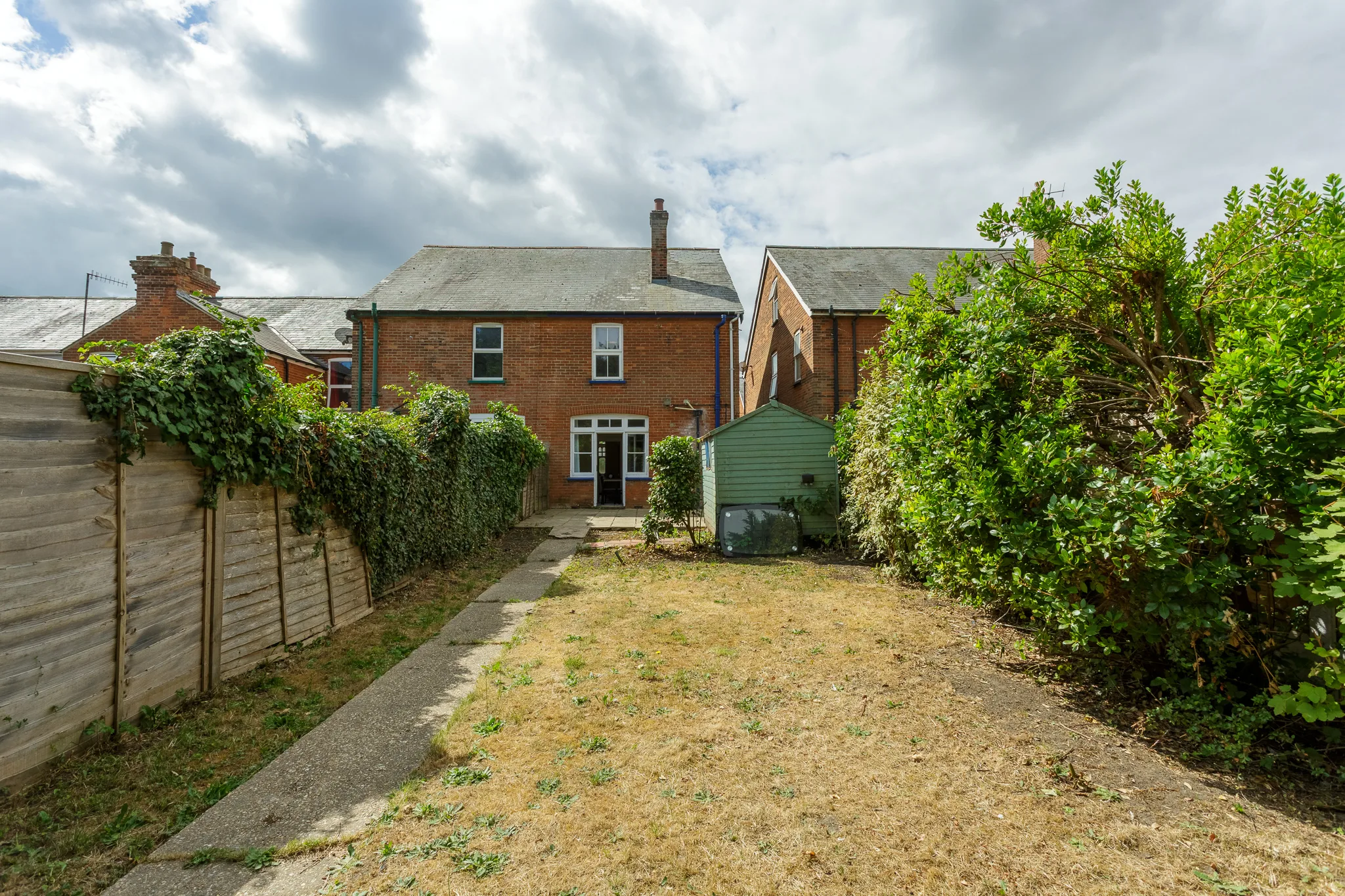 Red brick cottage with garden and green storage shed