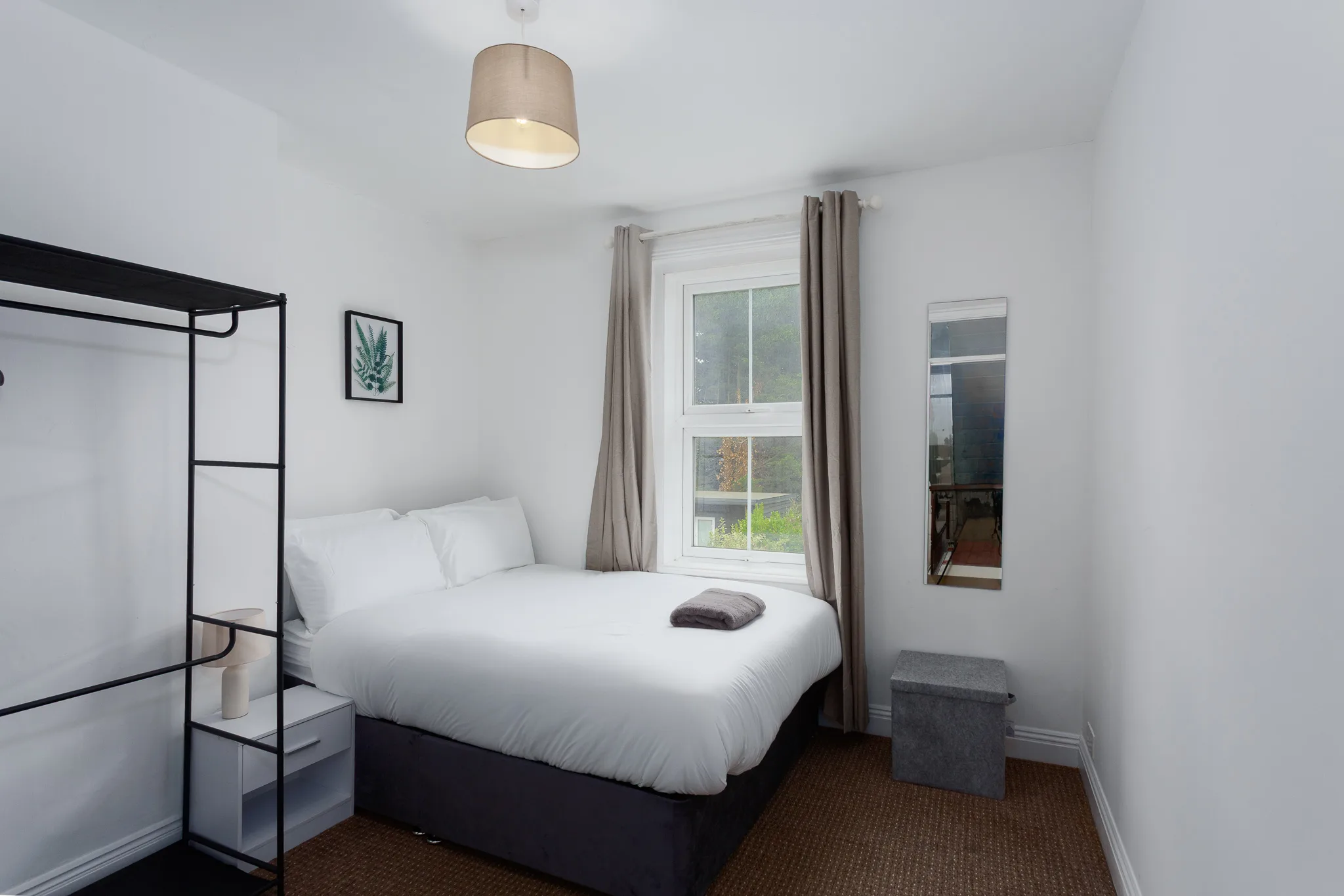 Modern bedroom with double bed, large window, and minimalist décor