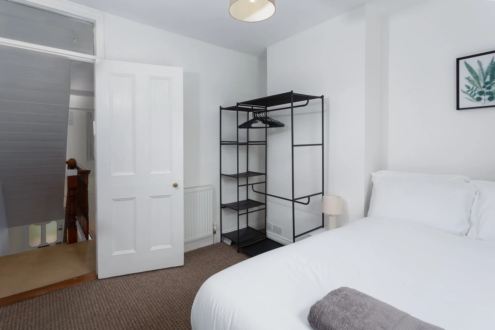 Modern bedroom with black metal wardrobe and white bedding
