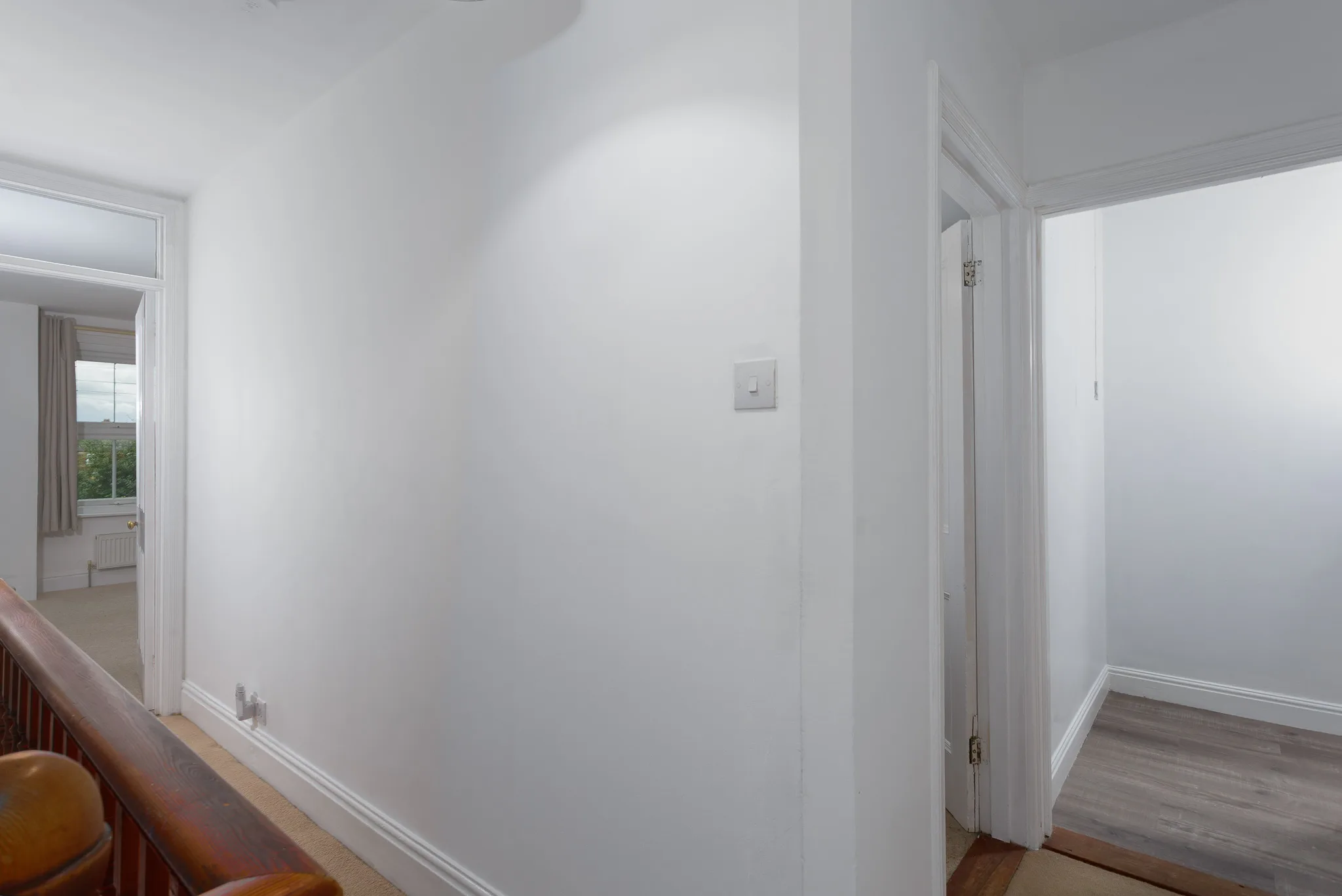 Bright minimalist hallway with white walls and wooden flooring
