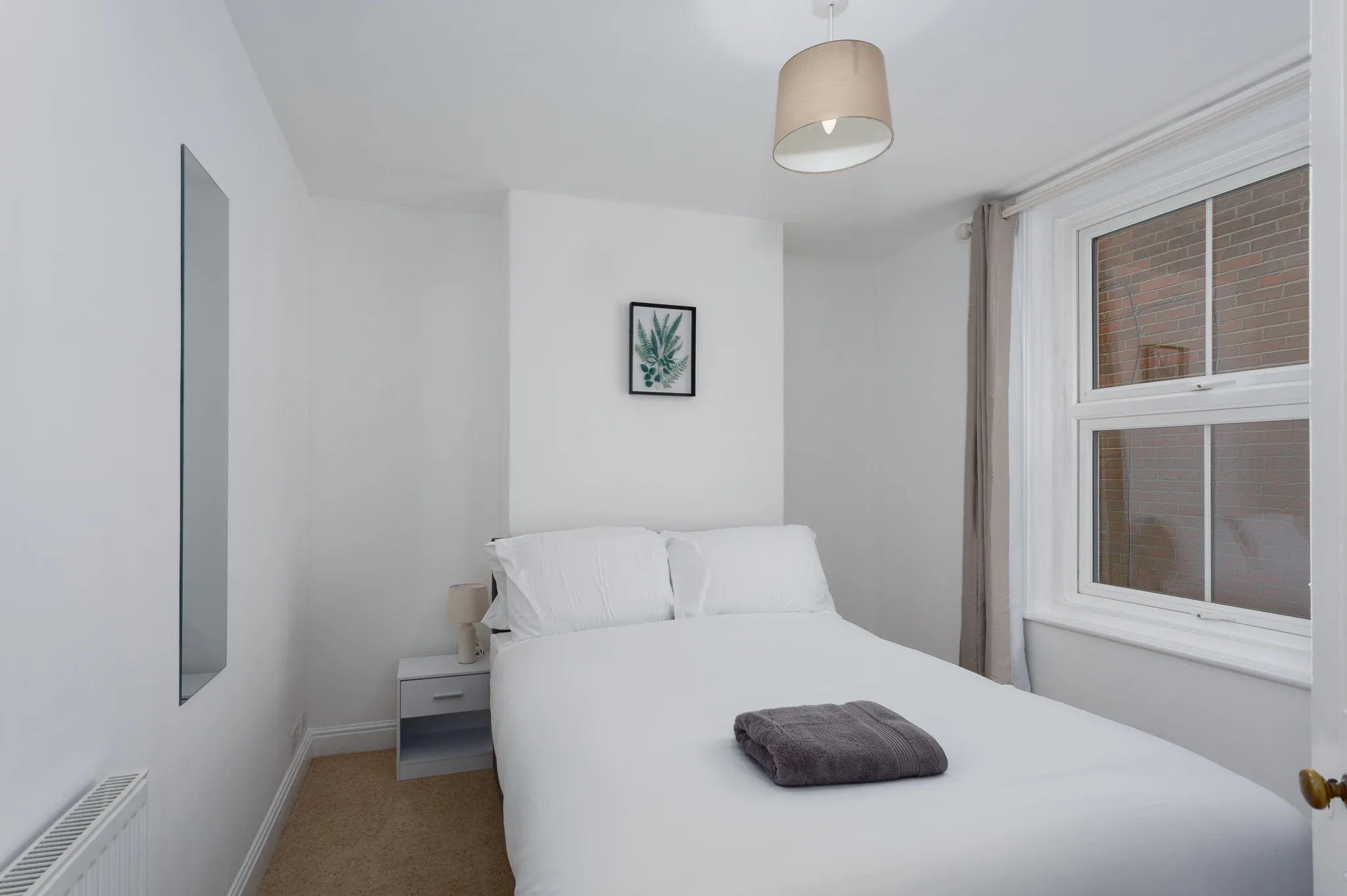 Minimalist bedroom with white bed and pendant light fixture