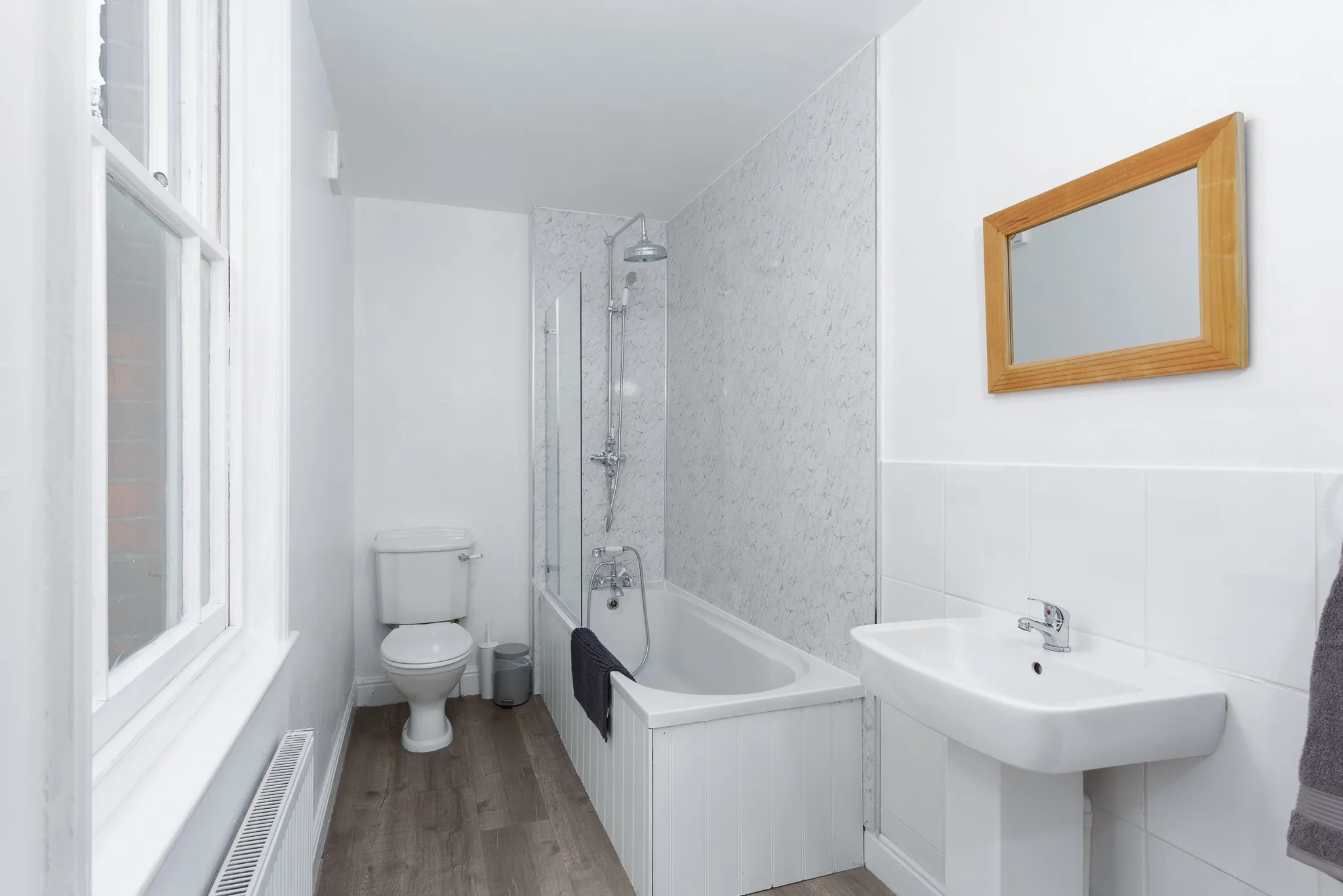 Modern bathroom with shower, toilet, sink and wooden mirror frame