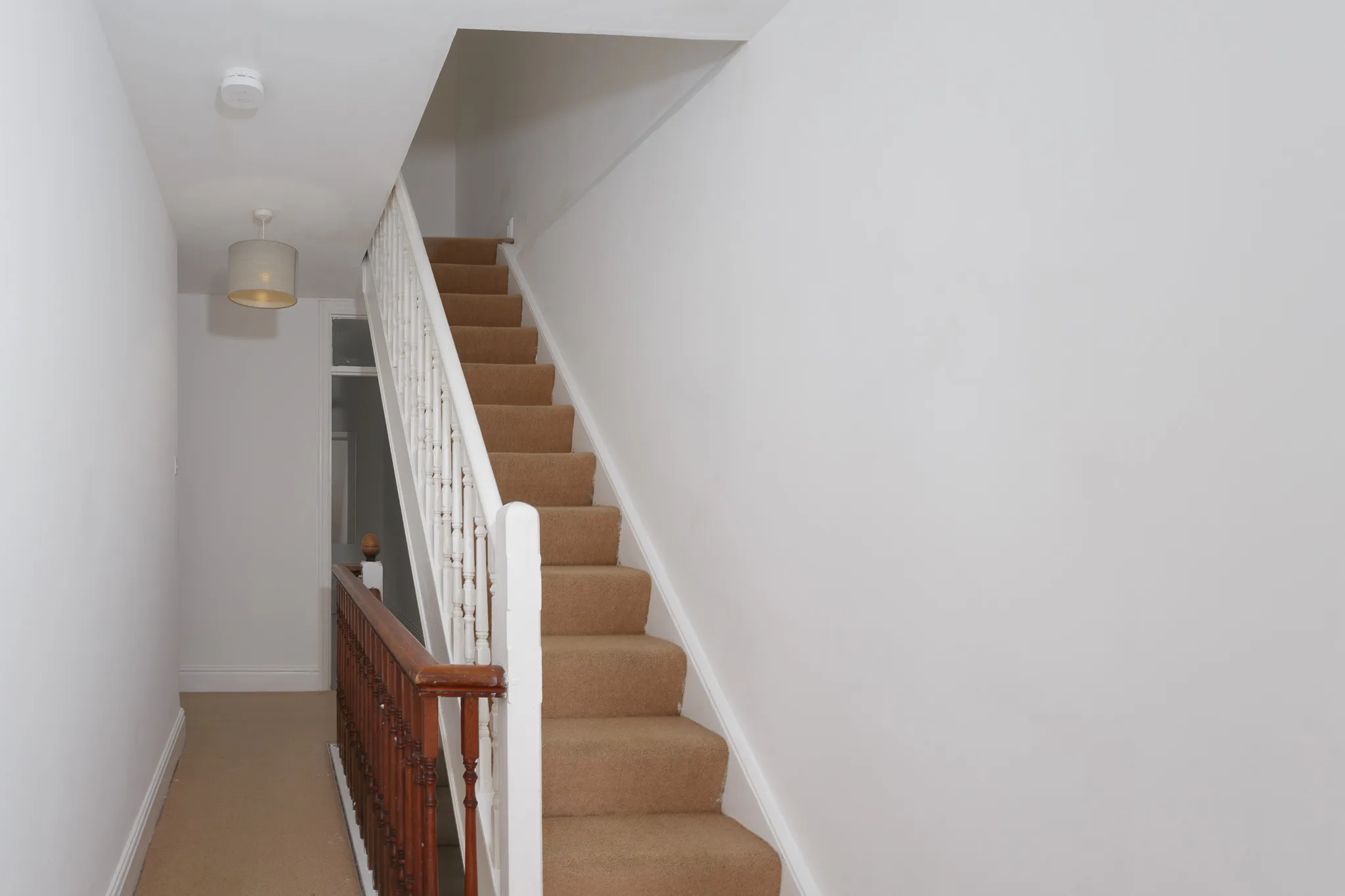 Modern staircase with white railings and beige carpet runner