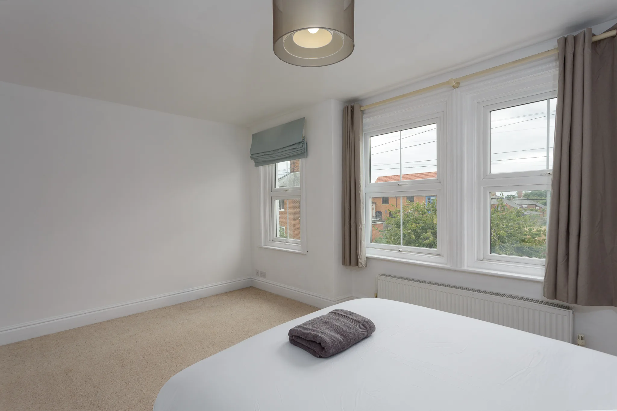 Modern bedroom with bed, multiple windows, and ceiling spotlight