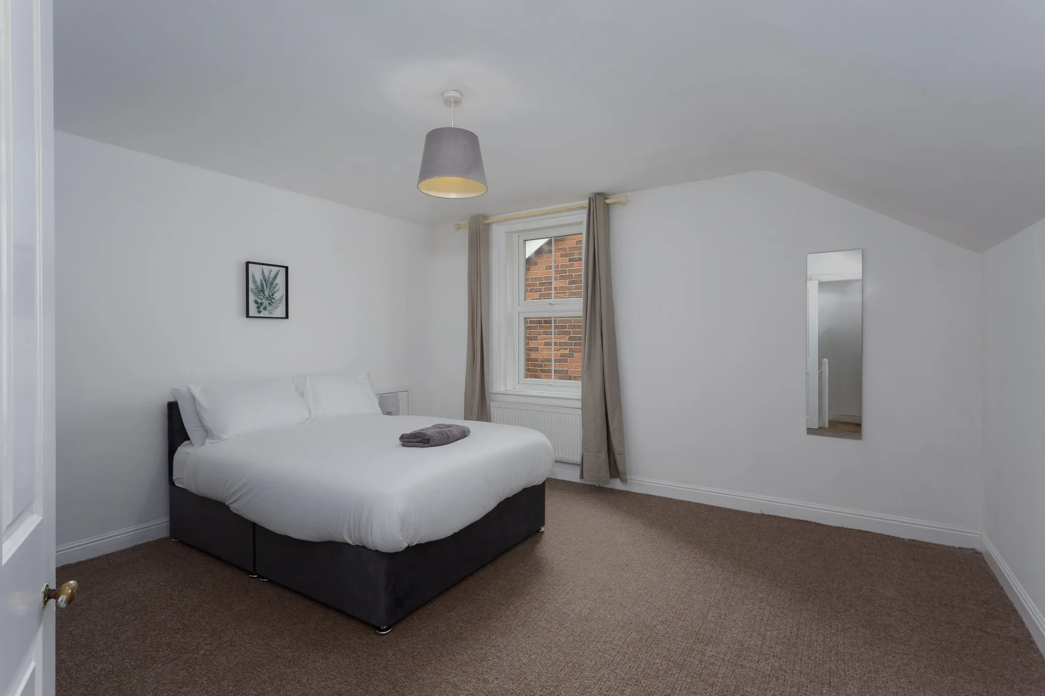 Modern bedroom with double bed, pendant light, brick window view