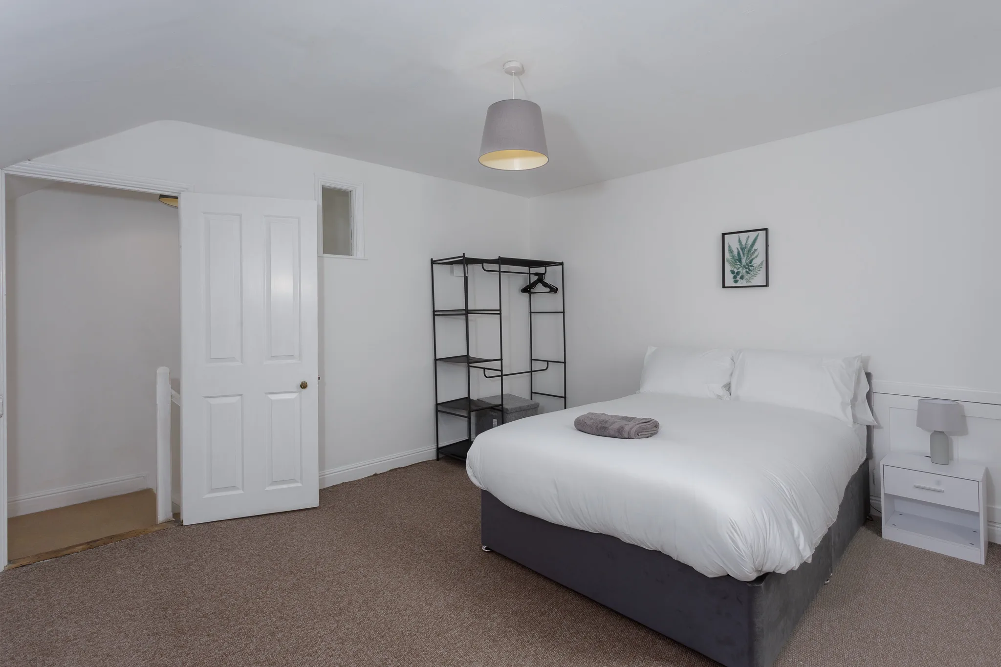 Modern bedroom with double bed, black wardrobe and white doors