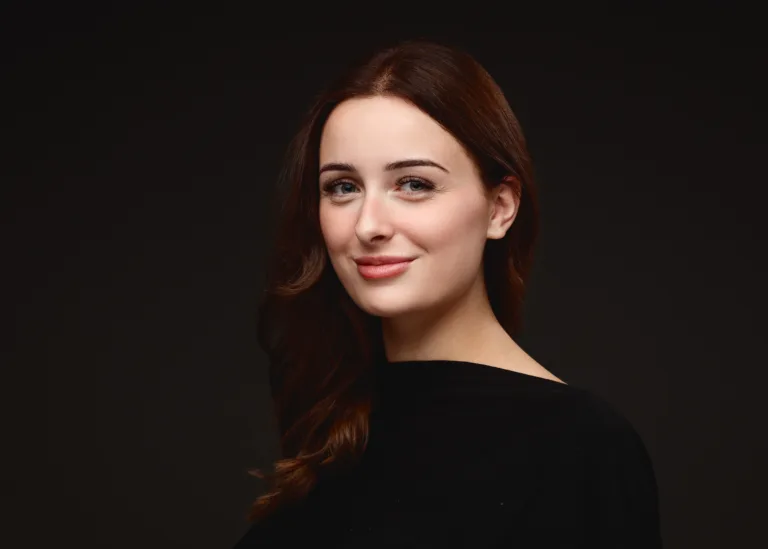 Woman with long reddish-brown hair against dark background