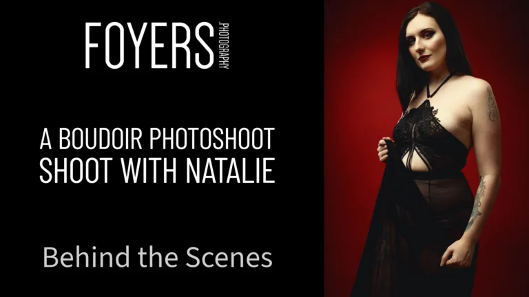 A woman in black lingerie poses against a red background for a boudoir photoshoot by Foyers Photography.